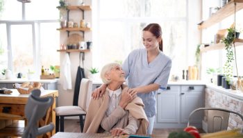 Pensioner feeling thankful. Aged grey-haired pensioner feeling thankful to her pleasant caregiver