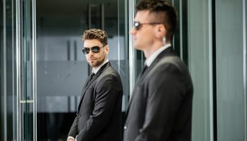 bodyguard service, hotel security, handsome man in suit and sunglasses standing in lobby near work