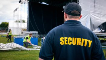 Rear View Of Security Team At Outdoor Stage For Music Festival Or Concert